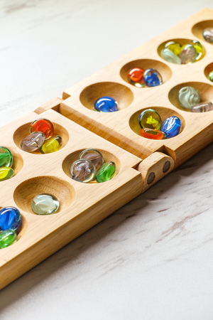 Traditional Mancala boardgame with glass pieces on marble tableの写真素材