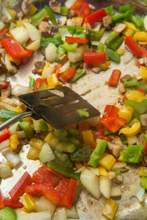 Cooking bell peppers onions and mushrooms for chicken fajitas in large stainless steel wok panの写真素材