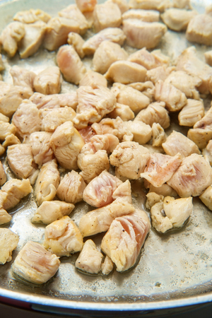 Cooking cubed bite size chicken in large stainless steel wok pan for fajitasの写真素材
