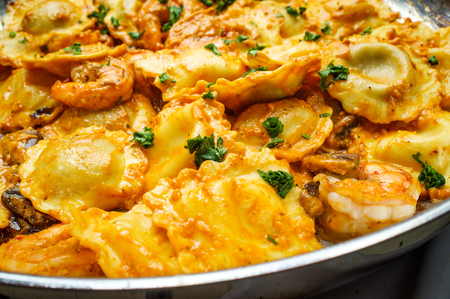 Italian shrimp and mushrooms with ravioli in pink creamy vodka sauce cooking on stovetopの写真素材