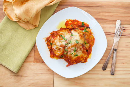 Home made Italian baked Eggplant parmesan on wooden kitchen tableの写真素材