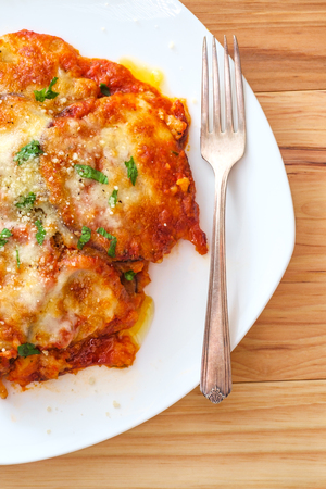 Home made Italian baked Eggplant parmesan on wooden kitchen tableの写真素材