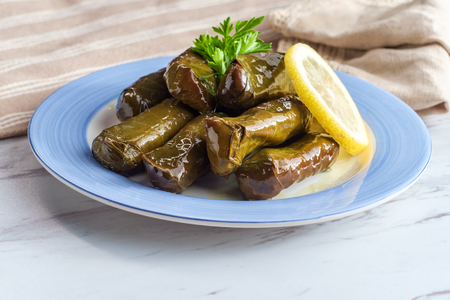 Armenian yaprak dolma, stuffed grape leaves garnished with lemon and fresh parsleyの写真素材