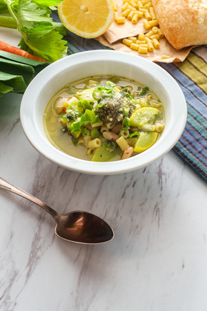Vegetarian minestrone soup topped with pesto scallions and grated parmesan cheeseの写真素材