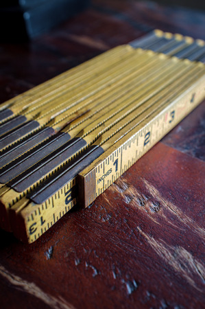 Old imperial folding ruler marked in inches on worn wooden floorの写真素材