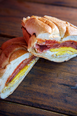 Taylor ham, pork roll, egg and cheese breakfast sandwich on a kaiser roll with salt pepper and...