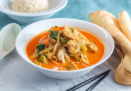 Thai food spicy coconut milk panang curry soup with chicken snow peas onions and spinachの写真素材