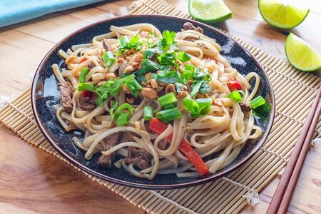 Authentic cuisine pad thai with beef rice noodles red bell peppers bean sprouts and lime garnish