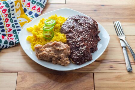 Mexican mole poblano chicken with rice and refried pinto beansの写真素材
