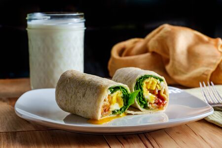 Egg and bacon American breakfast sandwich wrap with a glass of milkの写真素材