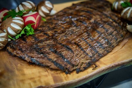 Thin grilled flank steak on wooden cutting boardの写真素材