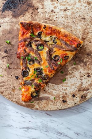 New York style slice of pizza with anchovies and black olivesの写真素材