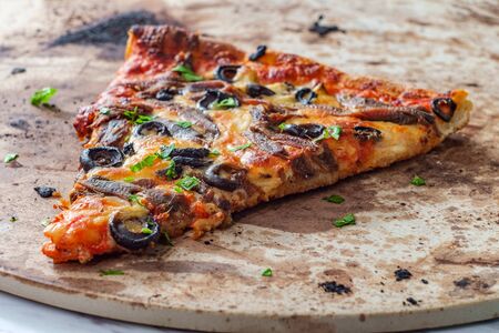 New York style slice of pizza with anchovies and black olivesの写真素材