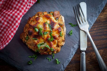 Stuffed seasoned large portobello mushroom on rustic slate slab with dark moody lightingの写真素材