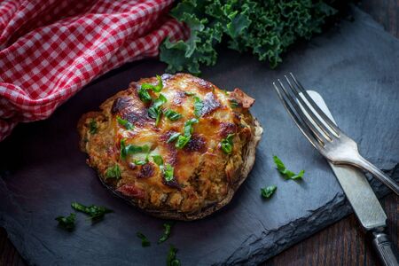 Stuffed seasoned large portobello mushroom on rustic slate slab with dark moody lightingの写真素材
