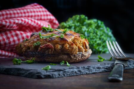 Stuffed seasoned large portobello mushroom on rustic slate slab with dark moody lightingの写真素材