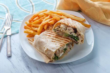 Chicken Caesar salad wrap sandwich with romaine lettuce and french friesの写真素材