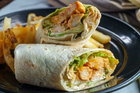 Grilled buffalo chicken sandwich wrap with romaine lettuce bleu cheese and friesの写真素材