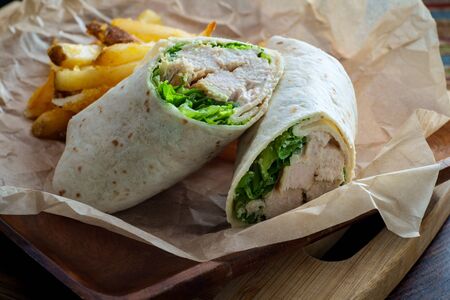 Chicken Caesar salad wrap sandwich with romaine lettuce and french friesの写真素材