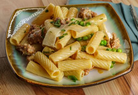 Italian rigatoni alfredo with hot and spicy sausage and green peas topped with shaved parmesan cheeseの写真素材