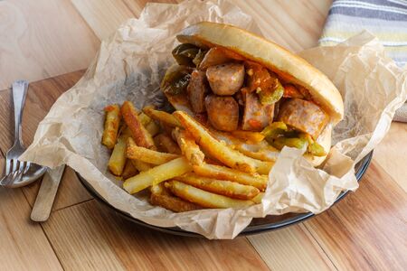Fried sausage onions and red green and yellow bell peppers on sandwich bunの写真素材