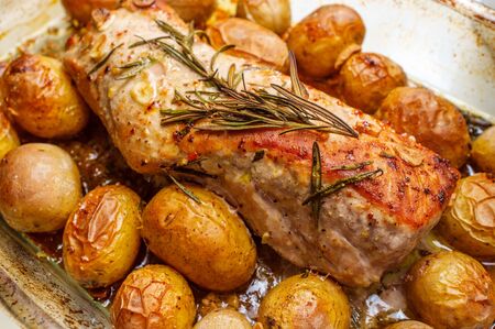 Honey mustard roast pork tenderloin with baby potatoes and rosemary garnish in oven casserole dishの写真素材