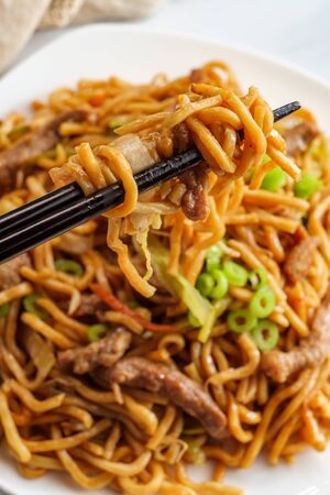 Eating Chinese beef lo mein noodles with chopsticksの写真素材