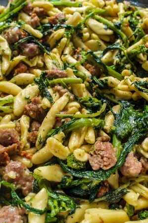 Italian spicy sausage ricotta cavatelli pasta and broccoli rabe simmering on kitchen stoveの写真素材