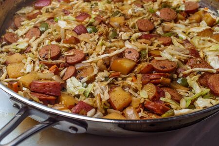 Cooking Polish kielbasa potatoes onions and peppers hash with cole slawの写真素材