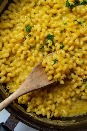 Delicious macaroni and cheddar cheese cellentani pasta cooking on kitchen stove
