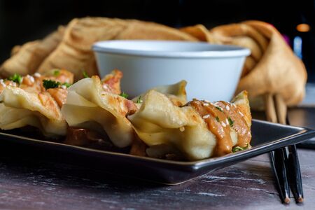 Fried Chinese Hunan pork dumplings with spicy peanut butter sauce and sesame seedsの写真素材
