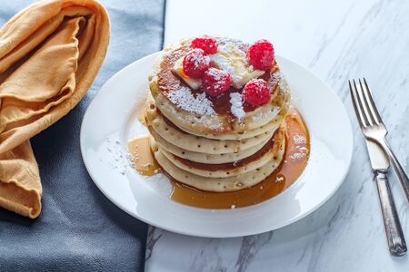 Pancakes with maple syrup powdered sugar raspberries and butter