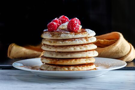 Pancakes with maple syrup powdered sugar raspberries and butter
