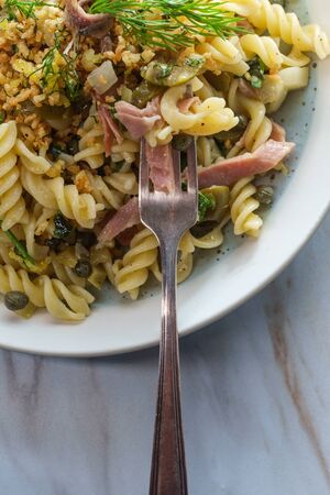 Castelvetrano olives Italian fusilli pasta mollicata with capers and prosciutto garnished with breadcrumbs in an anchovy white wine sauceの写真素材