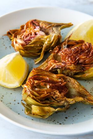 Italian fried halved artichoke with lemon wedgesの写真素材