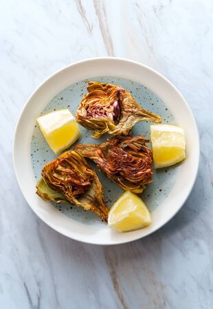 Italian fried halved artichoke with lemon wedgesの写真素材