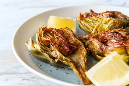 Italian fried halved artichoke with lemon wedgesの写真素材