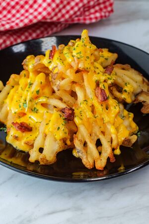 Crispy waffle fries loaded with bacon and melted cheddar cheese sauceの写真素材