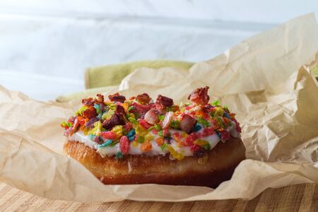Trendy bacon fruity rainbow cereal donut in parchment paper