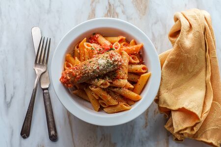 Gluten-free penne pasta in spicy arrabbiata tomato sauce with Italian sausageの写真素材