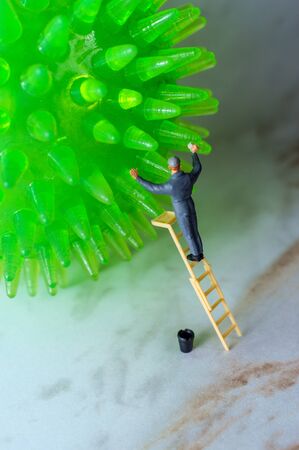 Window washer climbs ladder to clean coronavirus cells as metaphor for hand washingの写真素材