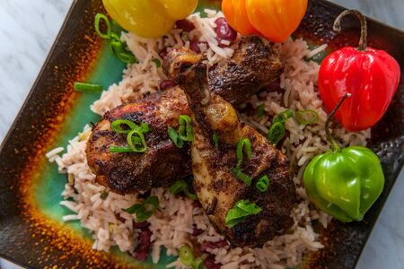 Authentic spicy Jamaican jerk chicken legs with scotch bonnet chili peppers served with coconut rice and peasの写真素材