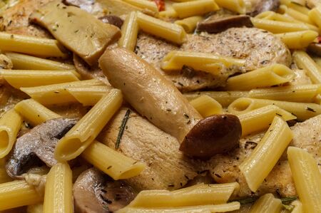 Cooking creamy Italian chicken marsala with King oyster mushrooms and sundried tomatoes served with penne rigate pastaの写真素材