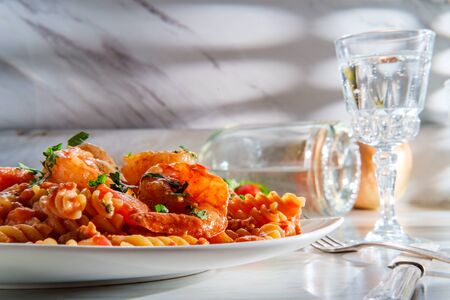 Gluten-free fusilli pasta in creamy vodka tomato sauce with sausage shrimp and green peasの写真素材