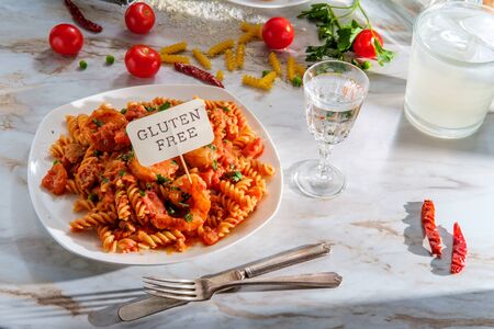 Gluten-free fusilli pasta in creamy vodka tomato sauce with sausage shrimp and green peasの写真素材