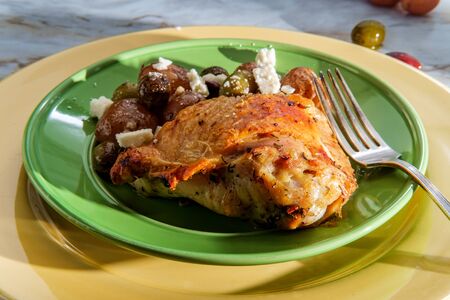 Greek skin-on bone-in chicken thighs with salmoriglio sauce with manzanilla and kalamata olives and new red potatoesの写真素材
