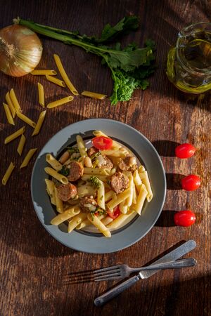 Italian spicy sausage penne pasta and broccoli rabe with dramatic lighting from windowの写真素材