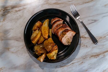 Roast pork tenderloin with sliced potato wedges in honey mustard gravyの写真素材
