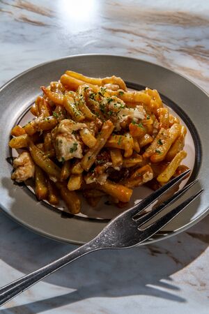 Canadian Poutine fries with gravy and cheese curd on marble kitchen table