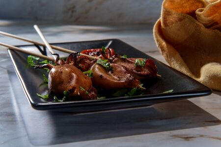 Seafood grilled squid satay kebab skewers with tentacles and sriracha hot sauce
